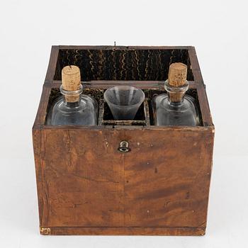 A birch veneered case with two bottles and a glass.