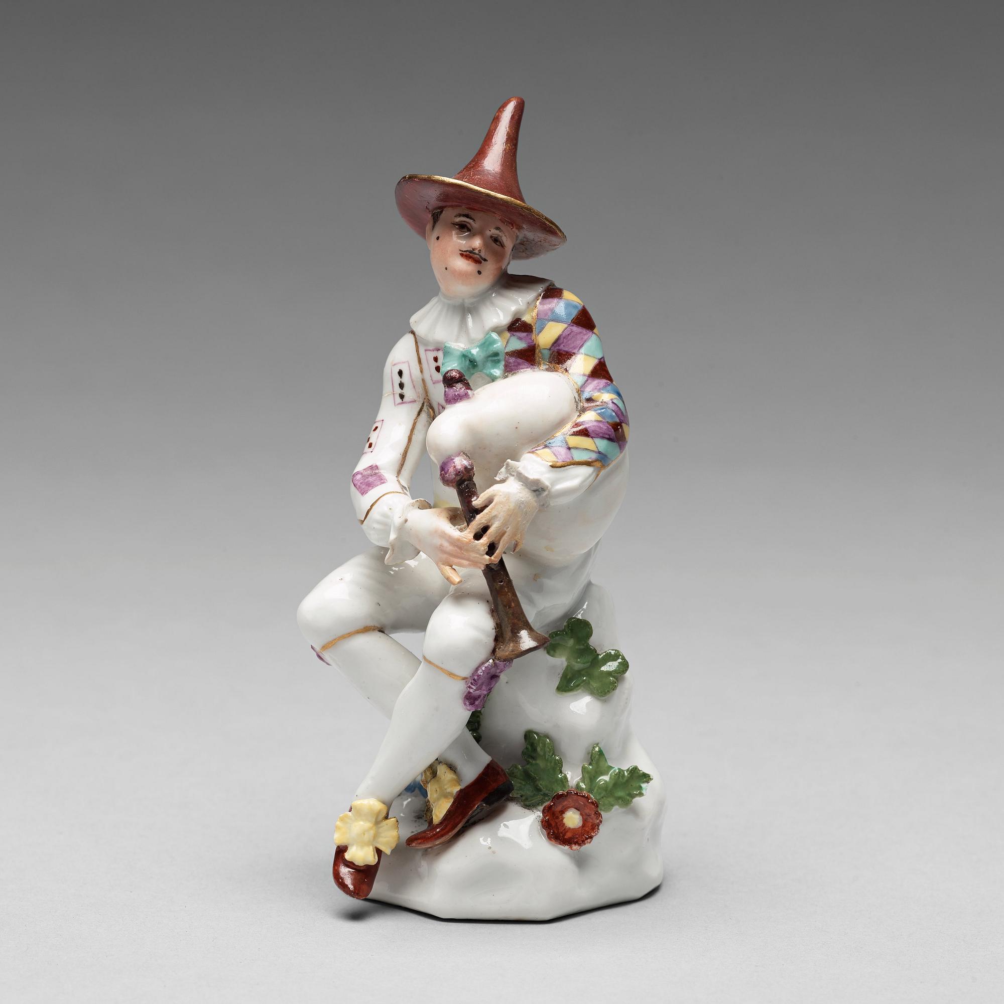 A porcelain figure of harlekin playing the bagpipe, circa 1900.