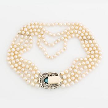 A four strand cultured pearl necklace with a clasp in 14K gold set with a faceted aquamarine.