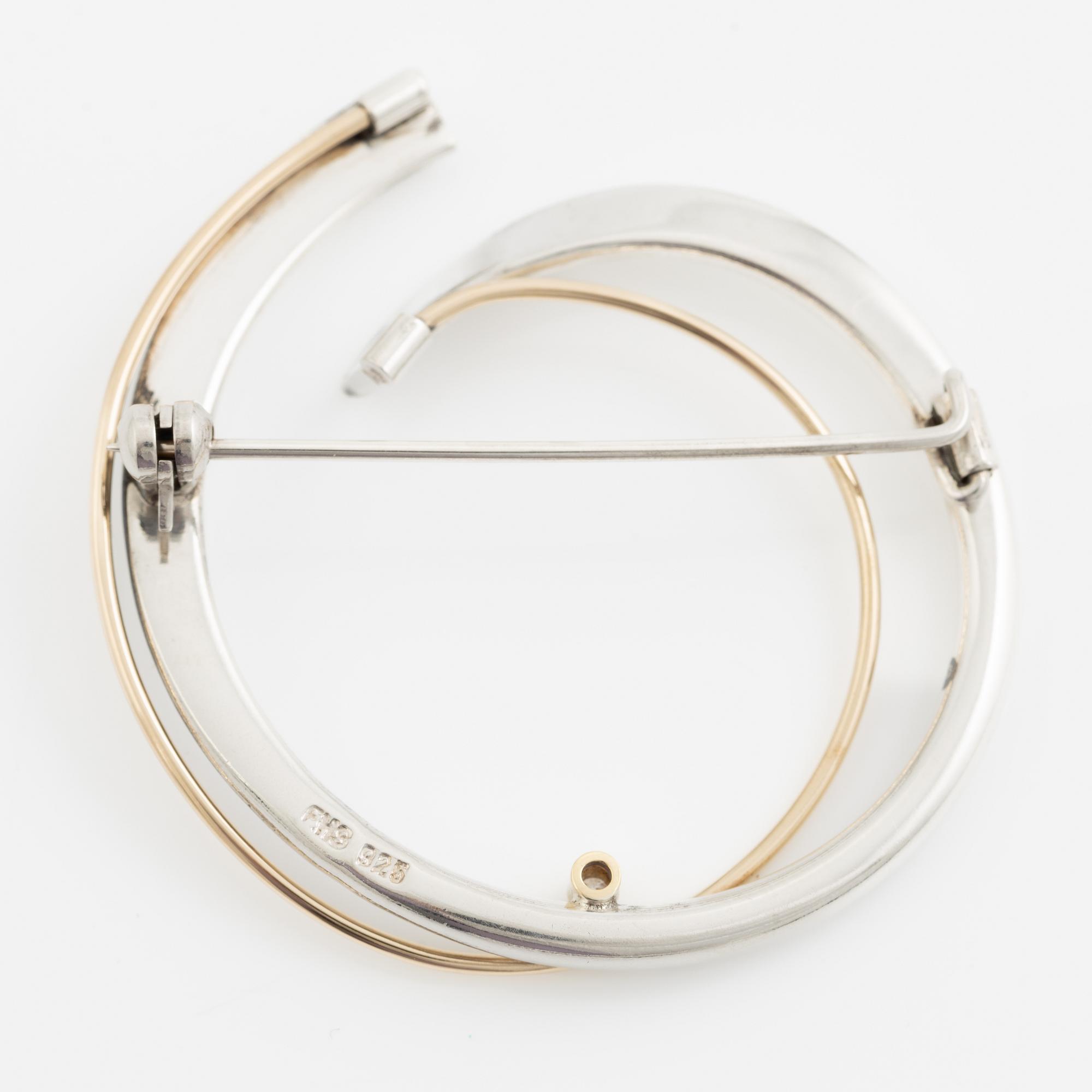 Brosch silver med en rund briljantslipad diamant.