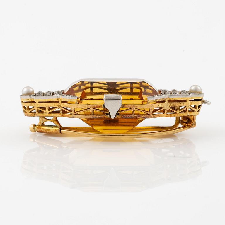 A brooch in 18K gold and platinum set with a faceted citrine.