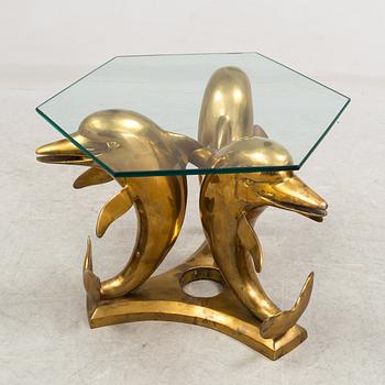 A brass and glass coffee table decorated with dolphins.