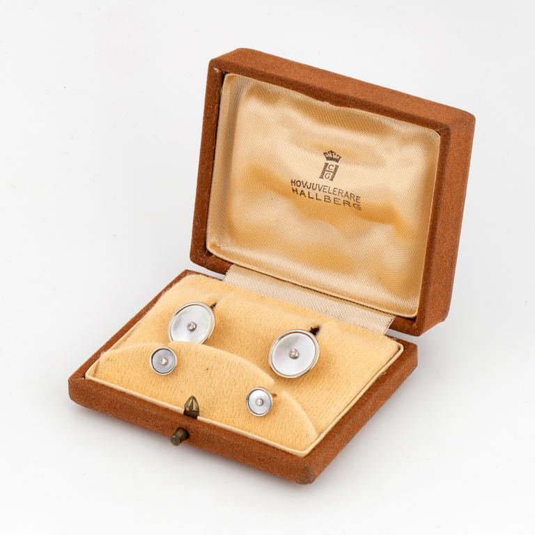A pair of cufflinks and a pair of shirt buttons.