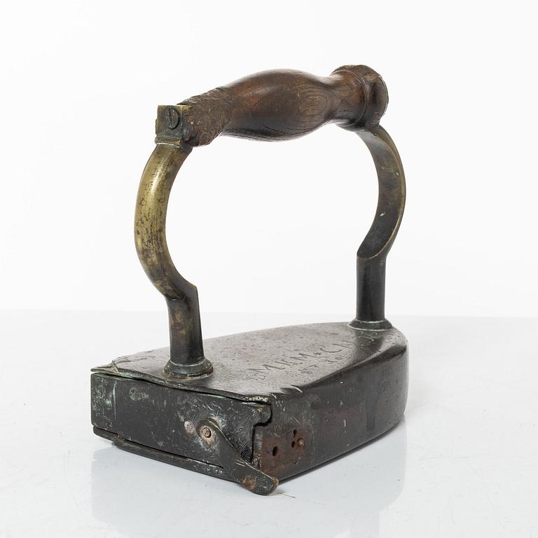 A brass clothes iron, dated 1710.