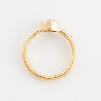 An 18K gold ring set with a round brilliant-cut diamond.