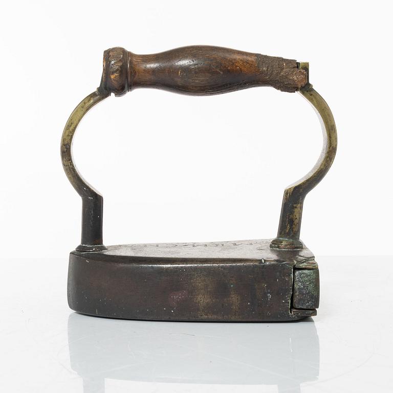 A brass clothes iron, dated 1710.