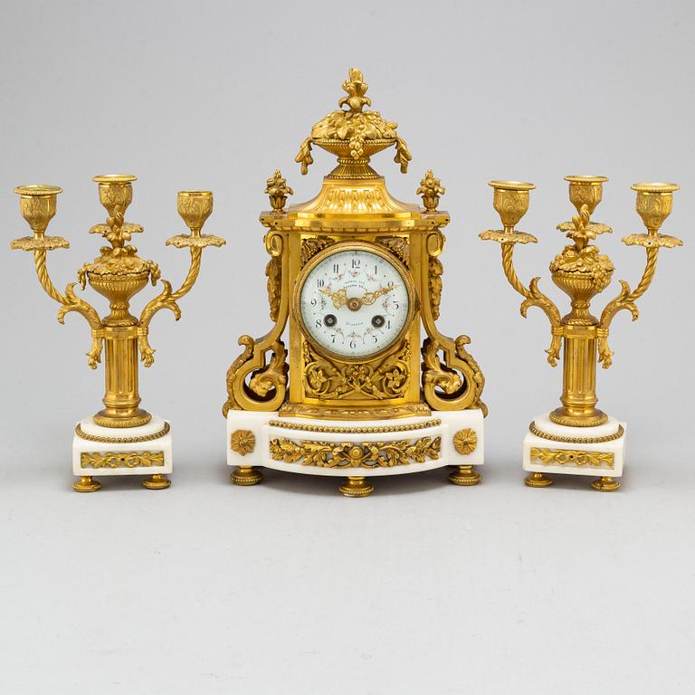 A late 19th century pendulum clock and a pair of candelabras.