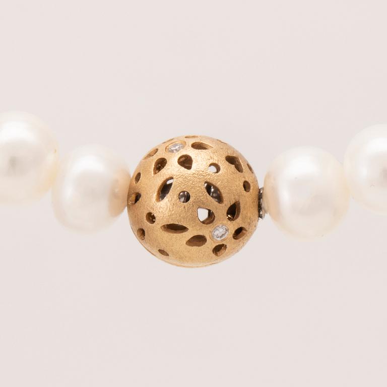 An 18K gold "Lace" lock by Ole Lynggaard set with round brilliant cut diamonds, necklace of cultured freshwater pearls.
