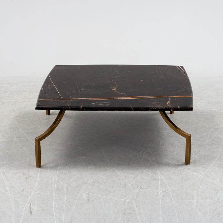 A modern Italian coffee table with black marble top on metal legs.