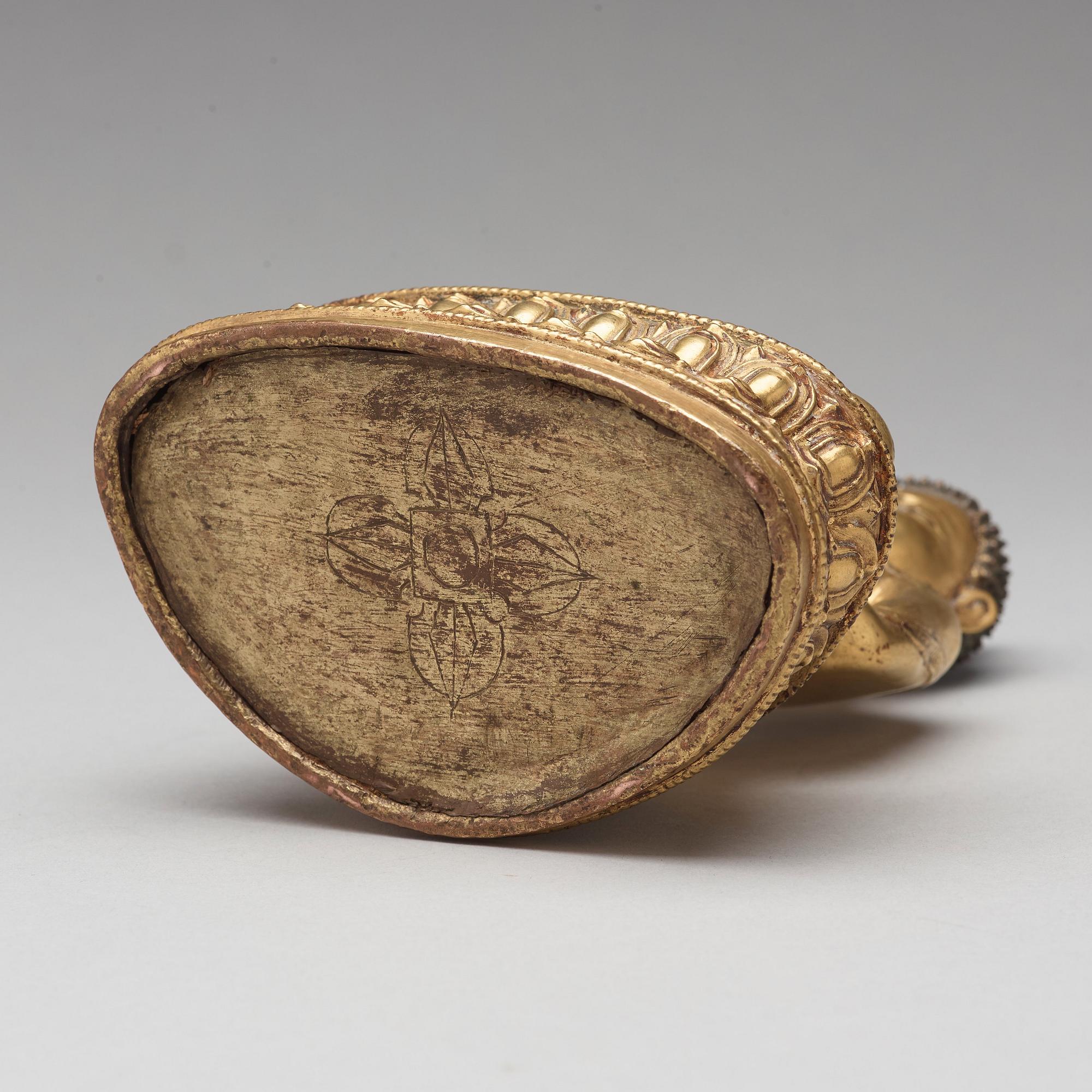 A gilt copper alloy figure of Akshobhya, Tibet, 16th Century.