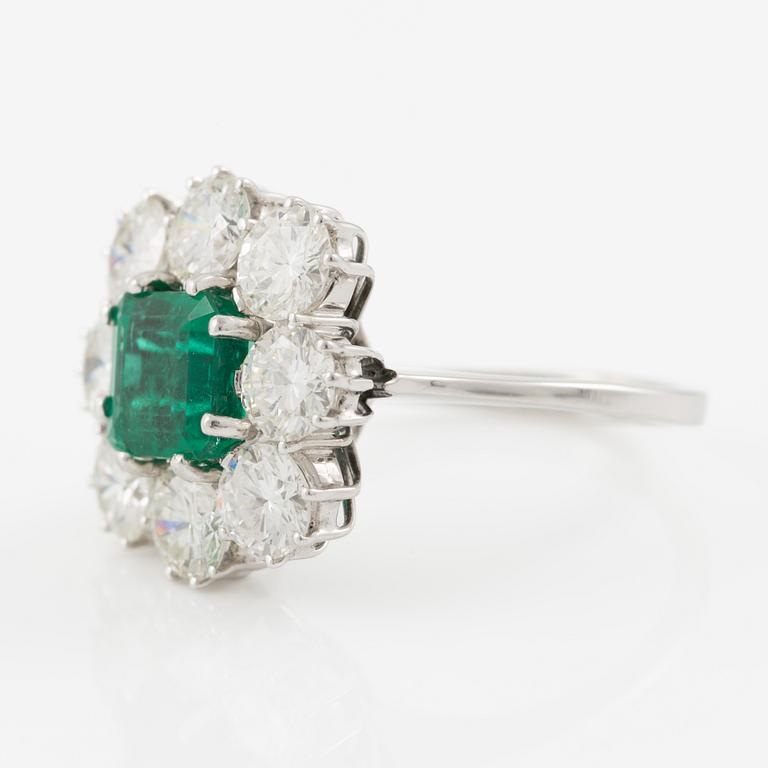 An 18K whitegold ring set with a step-cut emerald and round brilliant-cut diamonds.