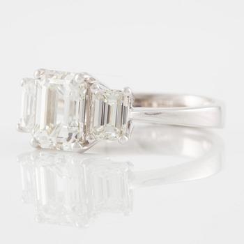 An 18K white gold ring set with three emerald-cut diamonds.