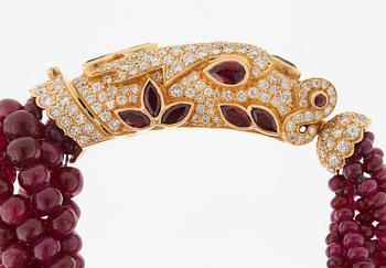 A Cartier chimera head bracelet in 18K gold set with round brilliant-cut diamonds and faceted rubies.