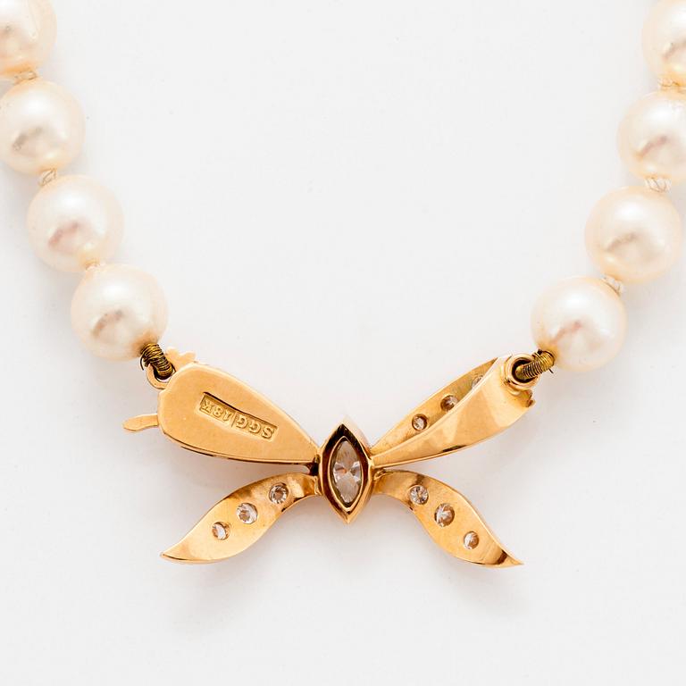 A cultured pearl necklace with a bow clasp in 18K gold set with round brilliant-cut diamonds.