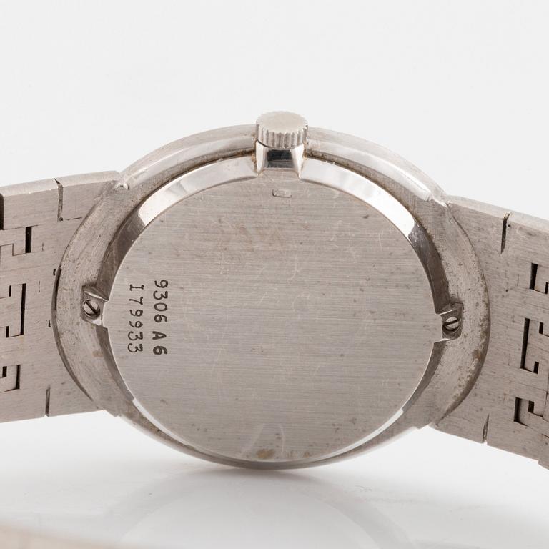 A Piaget 18K white gold wrist watch set with round brilliant-cut diamonds and step-cut emeralds.