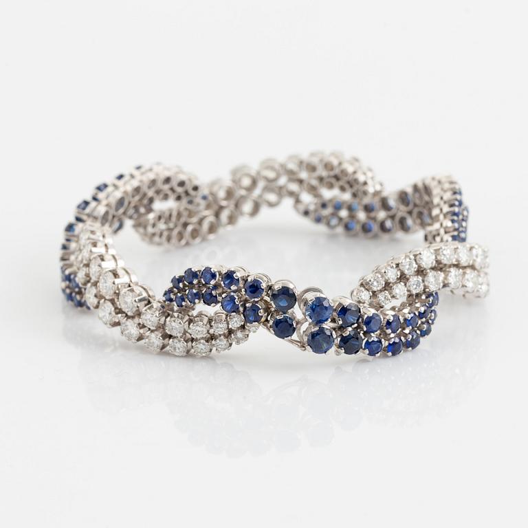 An 18K white gold bracelet set with round brilliant-cut diamonds and sapphires.