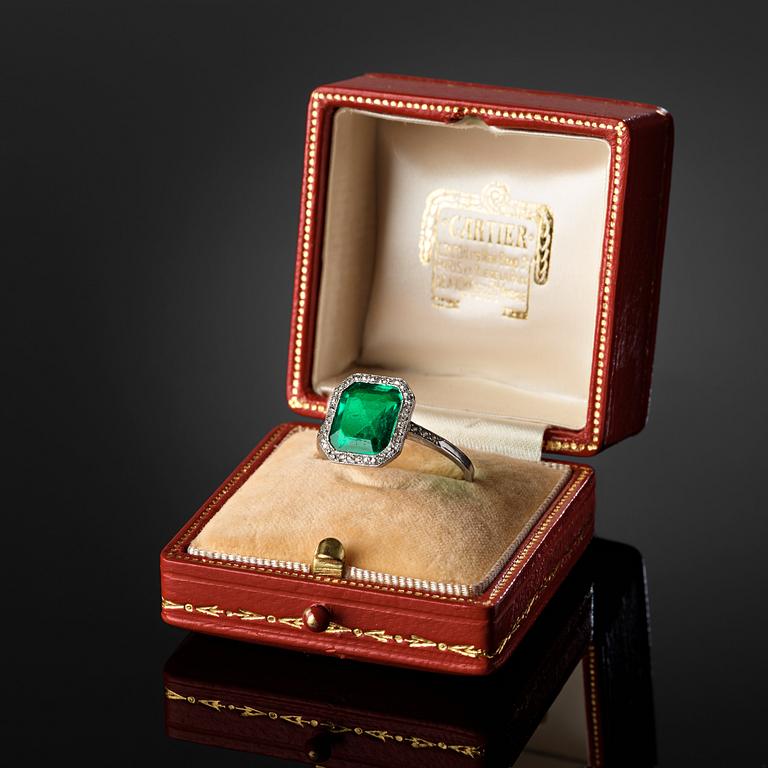 A platinum ring set with a Colombian step-cut emerald and old-cut diamonds in a fitted case from Cartier.