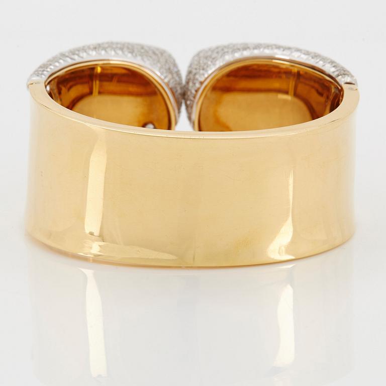 An 18K gold bangle set with round brilliant-cut diamonds.