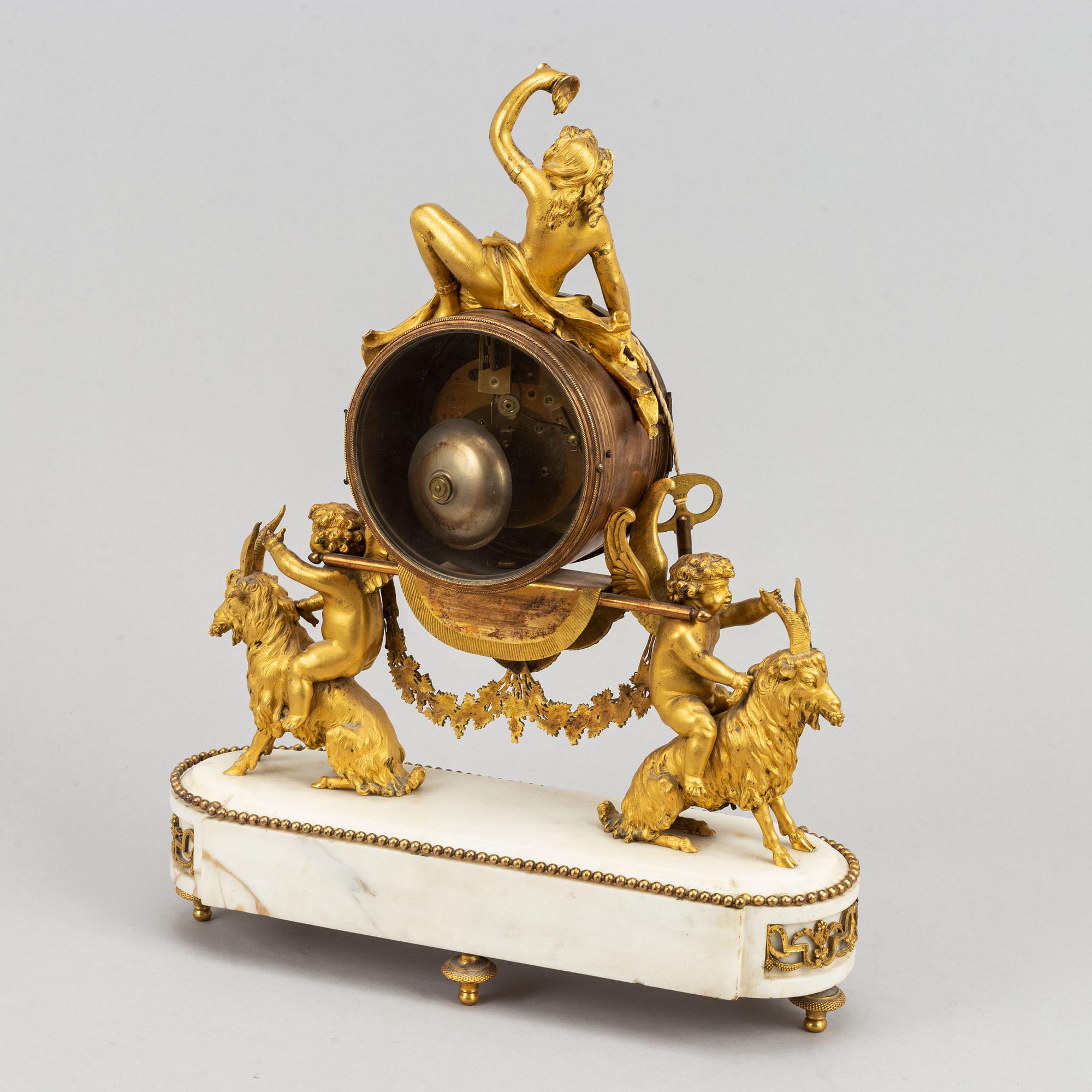 A marble and gilt bronze mantle clock in Louis XVI style, decorated with grapes, putti and a bacchant, 19th century.