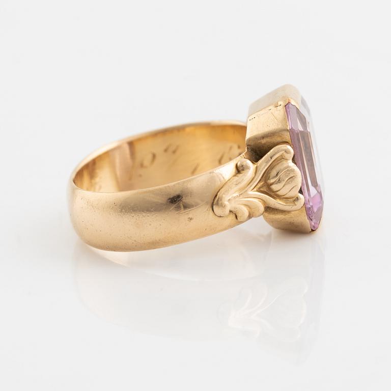 An 18K gold ring set with a pink stone.