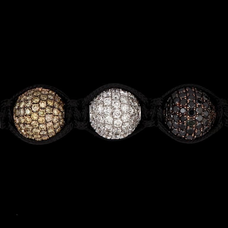 A bracelet in gold set with black, white and yellow diamonds.
