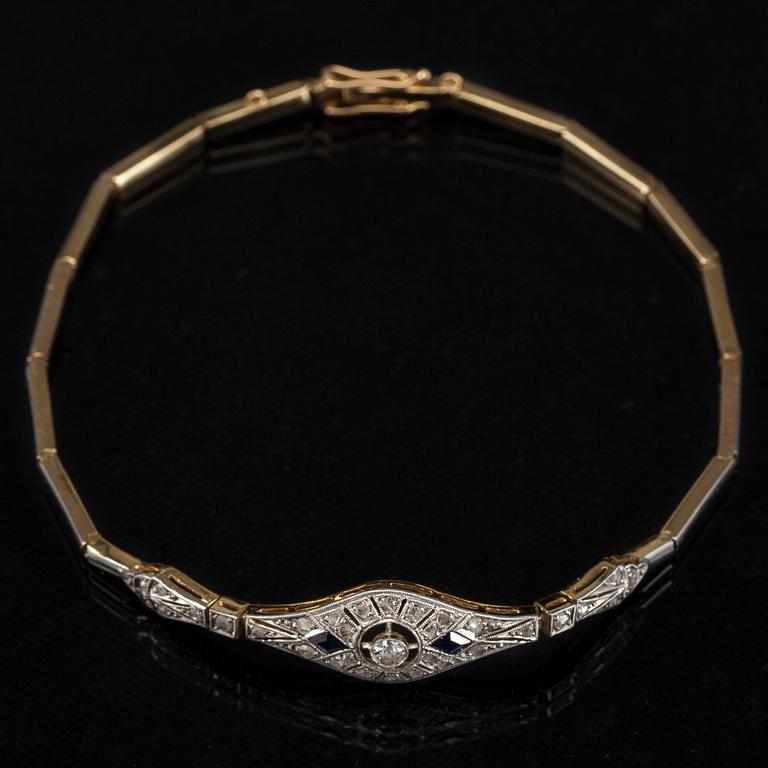 ARMBAND, 18K guld, fasettslipad diamant ca 0.08 ct, 2 blå safirer samt rosenstenar, 1900-talets första hälft. Vikt 8 g.