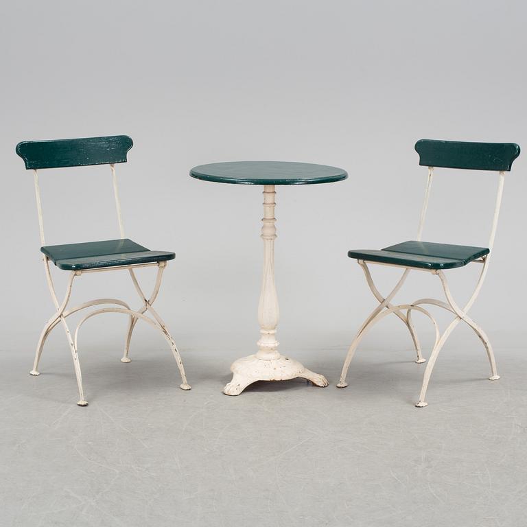 A pair of cast iron chais with wooden seats and a cast iron table, early 20th century.