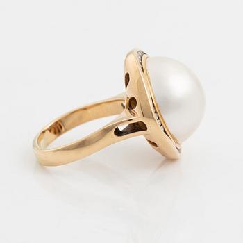 A 14 k gold ring set with a half pearl and round brilliant-cut diamonds.
