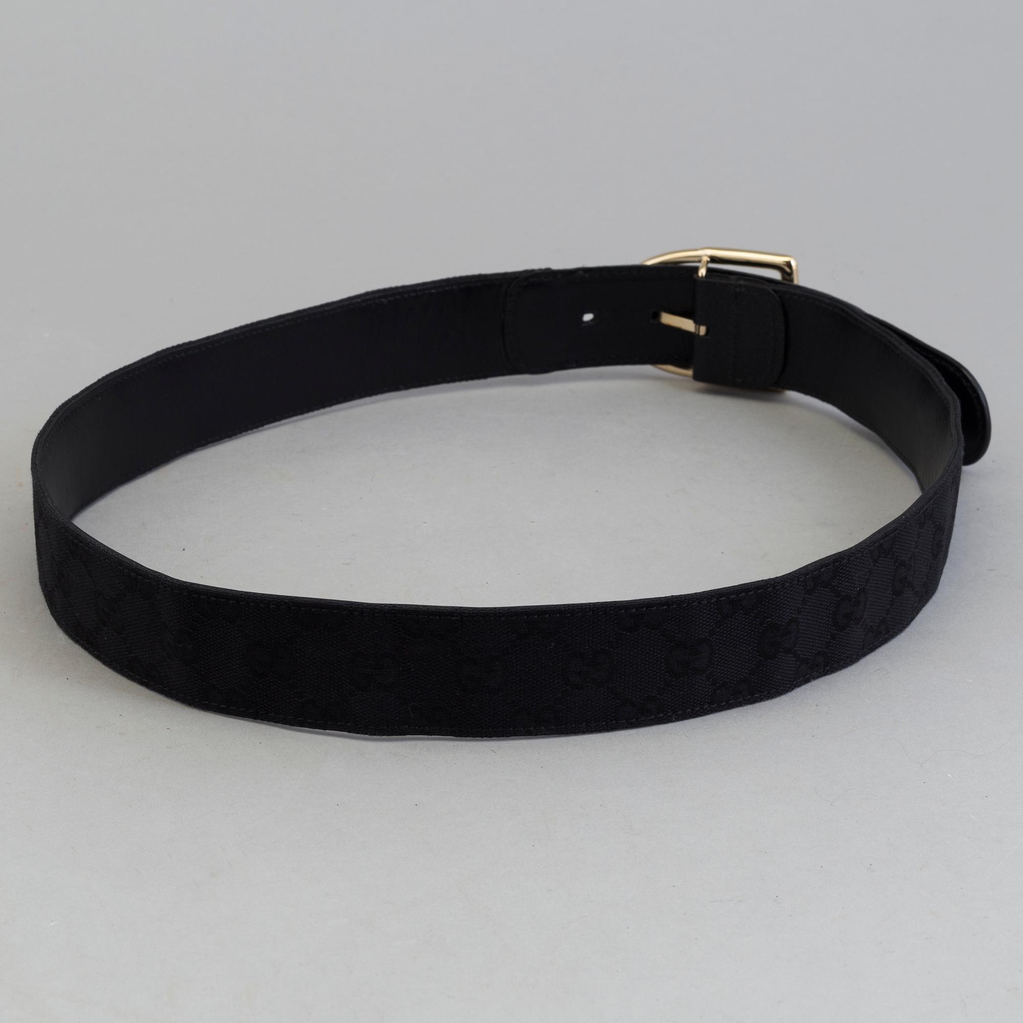 A blach monogram belt by Gucci.