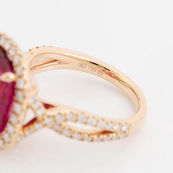 An 18K gold ring set with a faceted pink tourmaline and round brilliant-cut diamonds.