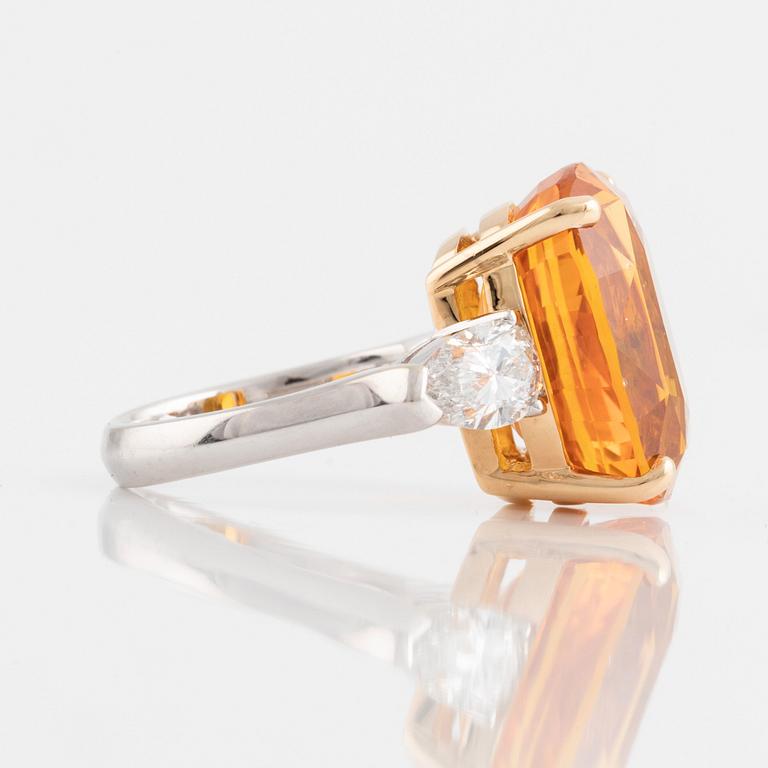 An 18K white gold ring set with a cushion shaped orange-yellow sapphire.