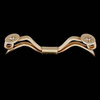 SPÄNNE, 18k guld med 2 briljantslipade vita stenar, Nils Ahlström, Borås, 1953. Vikt 6 g.