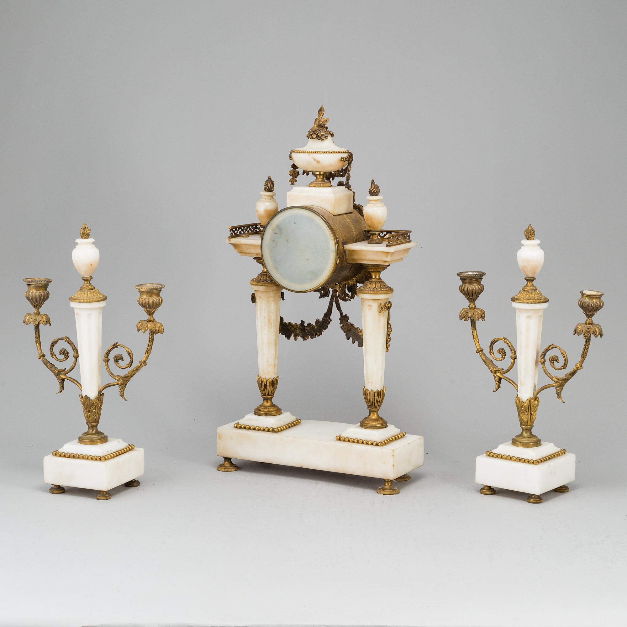 A Louis XVI-style mantle clock and a pair of candelabras. Early 20th century.