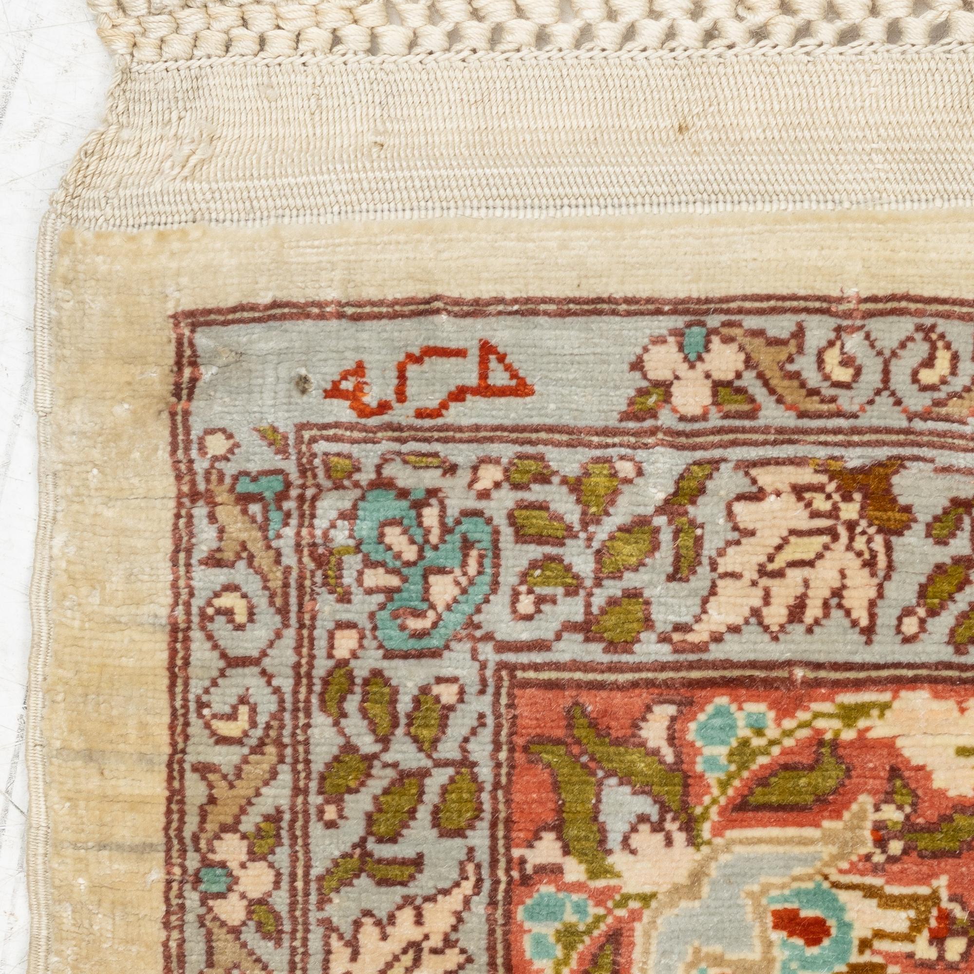 A silk Hereke rug, c. 85 x 55 cm.