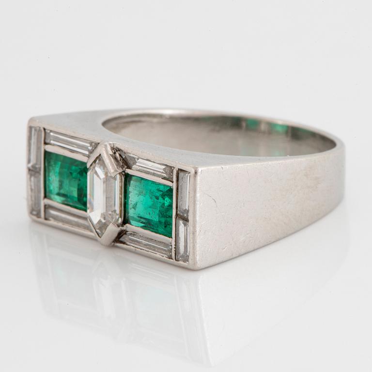 A platinum ring set with faceted emeralds and diamonds.