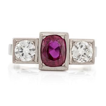 A platinum ring with a faceted ruby and two round brilliant-cut diamonds.