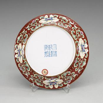 A Canton enamel ruby-red ground dish decorated with lotus flowers, Qianlong seal mark and period (1736-1795).