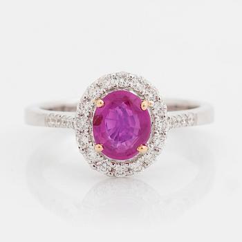 An 18K white gold ring set with a faceted pink sapphire and round brilliant-cut diamonds.