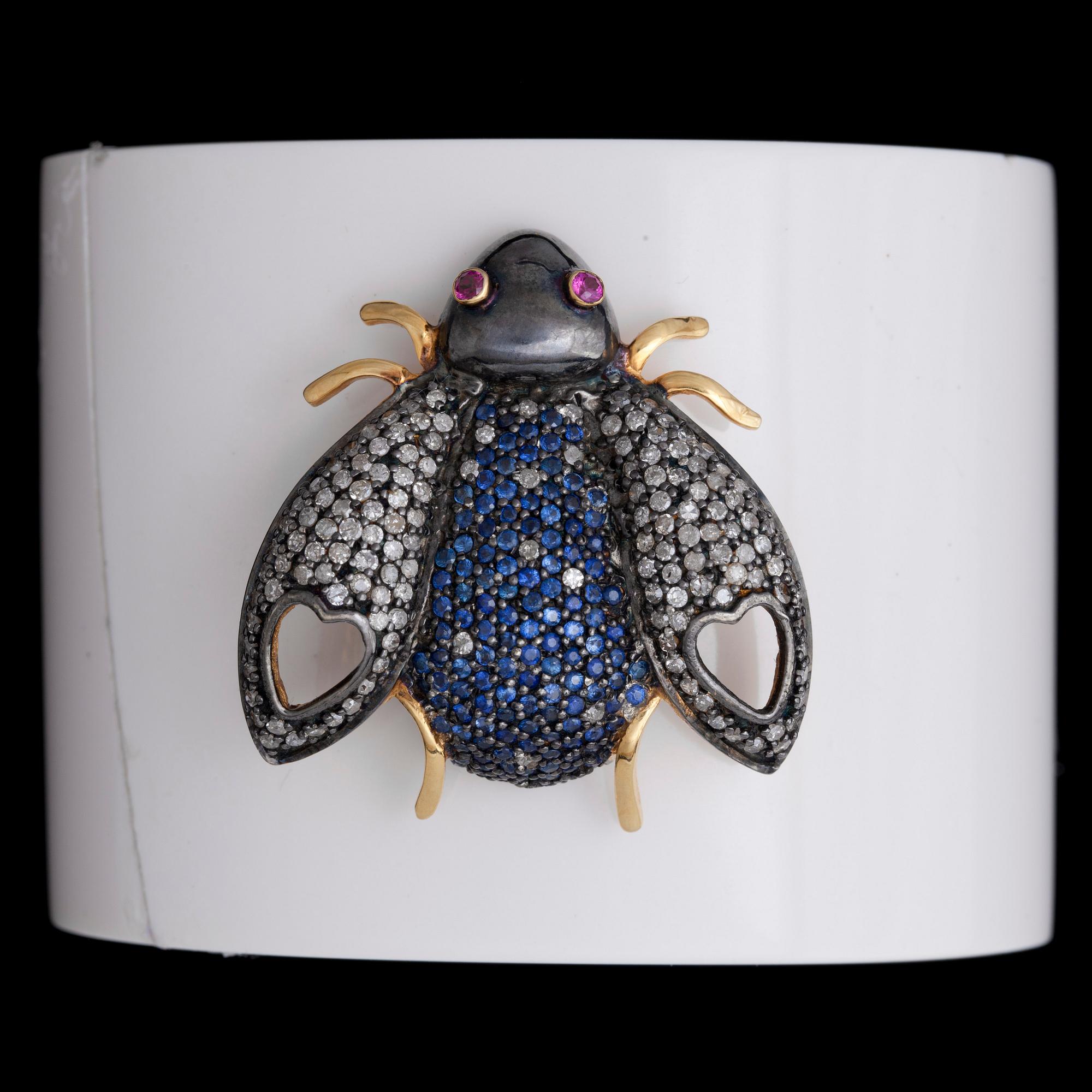 ARMRING, förgyllt silver, diamanter, safirer samt rubiner på vit bakelit.