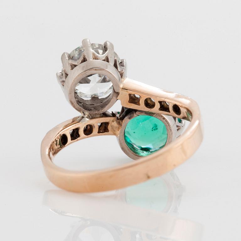 A CROSS-OVER RING set with an old-cut diamond and a round mixed-cut emerald.