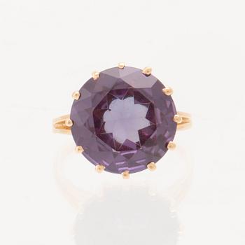 An 18K gold ring set with a round faceted colour-changing synthetic purple sapphire, Heribert Engelbert Stockholm.