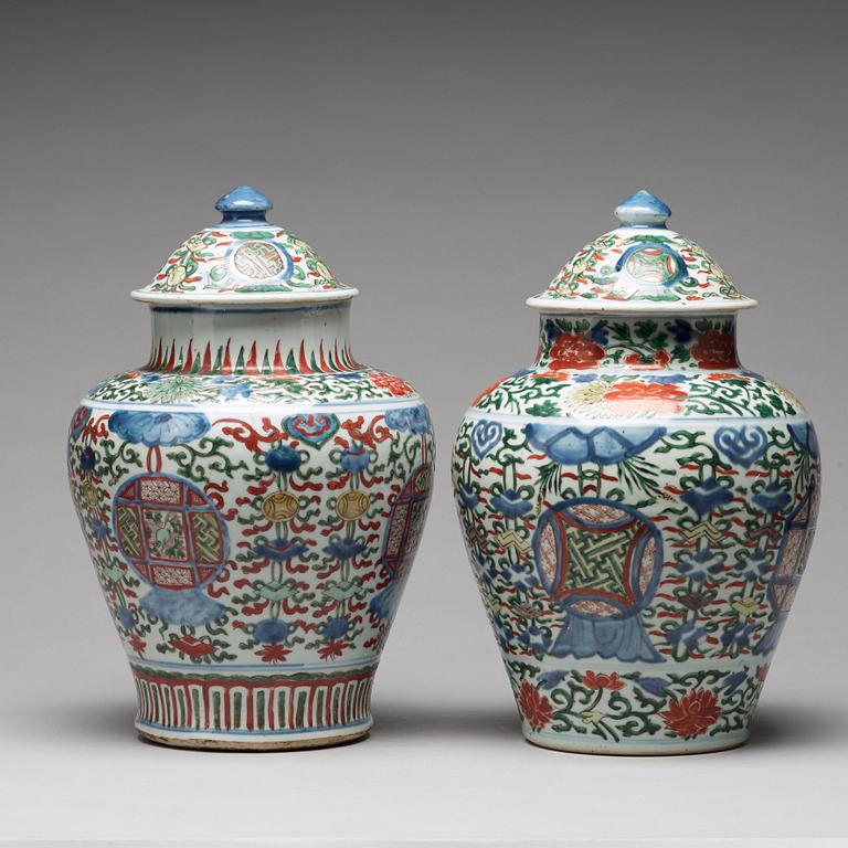 A matched pair of Transitional wucai baluster vases with covers, 17th Century.