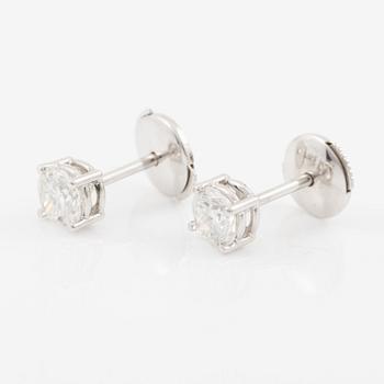 A pair of earrings in 18K white gold set with two round brilliant-cut diamonds.