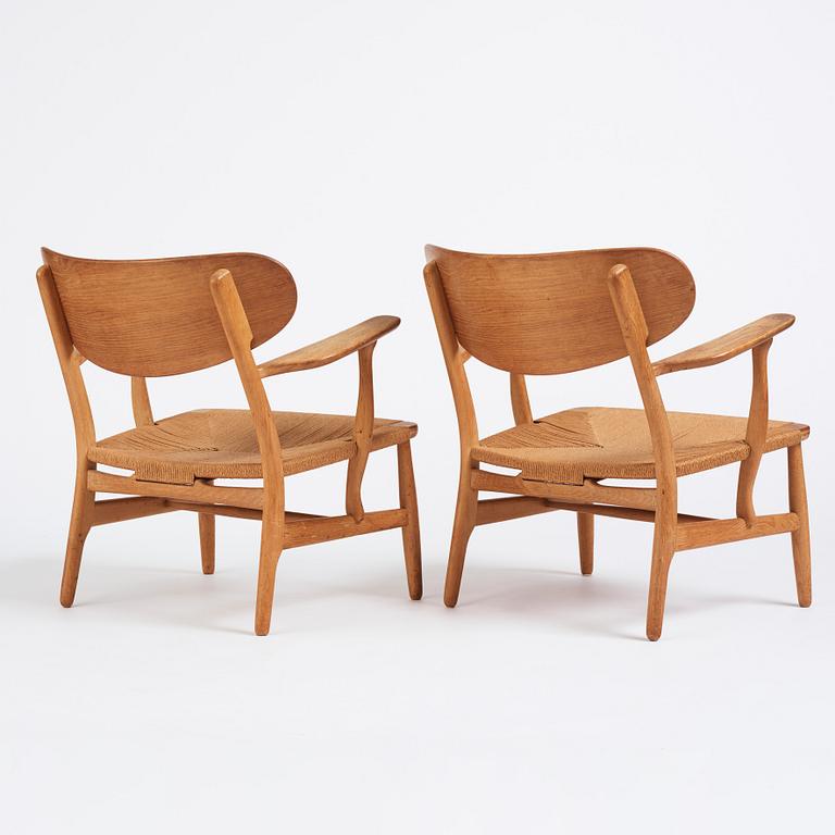 Hans J. Wegner, a pair of "CH 22" oak chairs, Carl Hansen & Son, Odense, Denmark, mid 20th century.