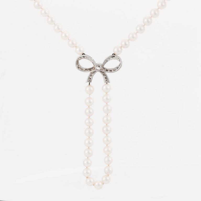 A cultured pearl necklace with a 14K white gold bow pendant set with round brillliant-cut diamonds.