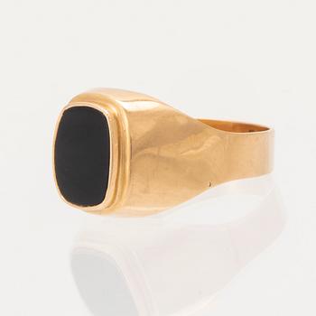 An 18K gold ring set with a black stone.