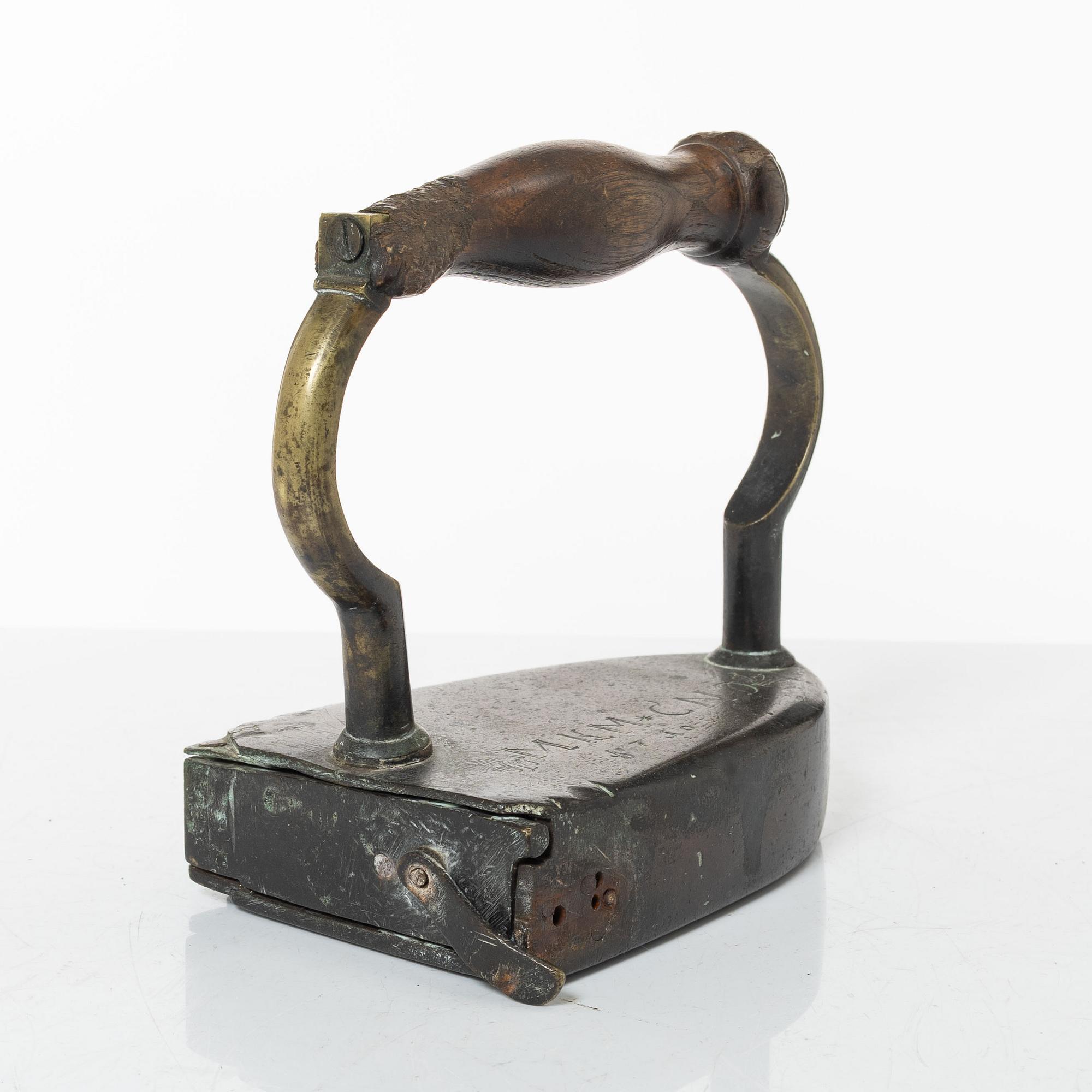 A brass clothes iron, dated 1710.
