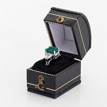 An 18K white gold ring, set with a Zambian emerald and trillion-cut diamonds.