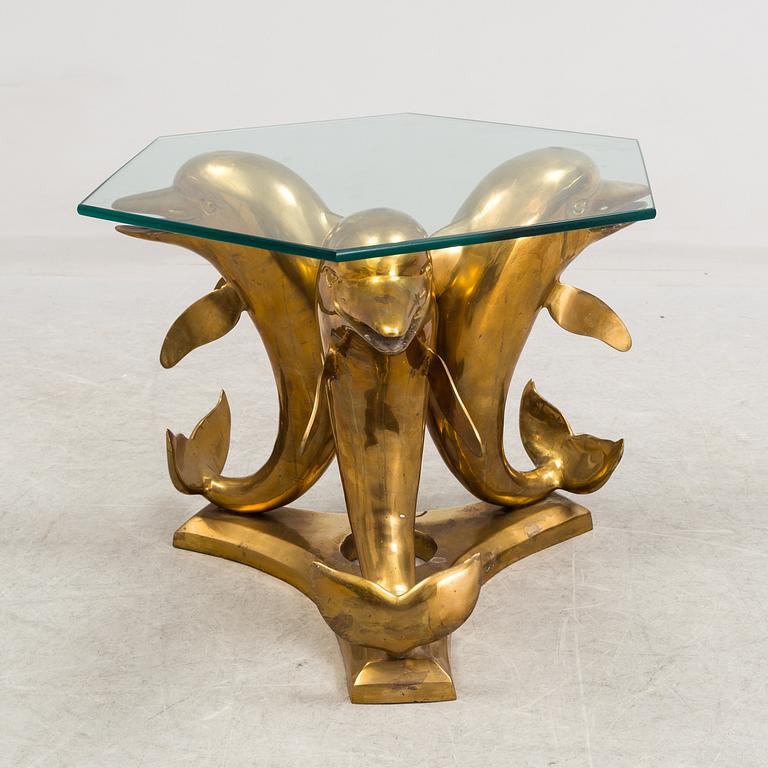 A brass and glass coffee table decorated with dolphins.