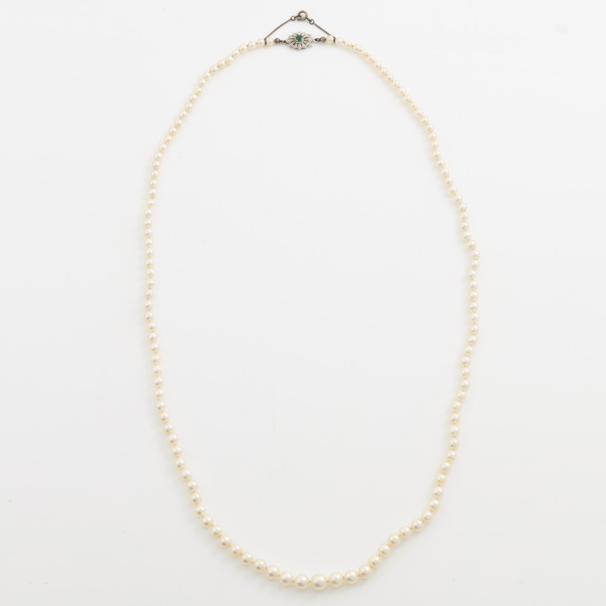Necklace with graduated cultured pearls, with a clasp in 18K white gold set with an emerald.